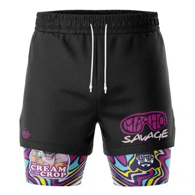 The Cream of the Crop Trippy Randy Savage 2-in-1 Performance Shorts feature black athletic shorts with “Macho Savage” in pink on the right leg and attached colorful compression leggings with cartoon graphics, swirls, and the phrase The Cream of the Crop.