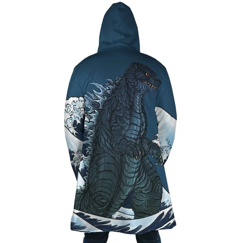 A person wearing the Godzilla Dream Cloak Coat, which features a large, detailed illustration of Godzilla emerging from stylized ocean waves on the back.