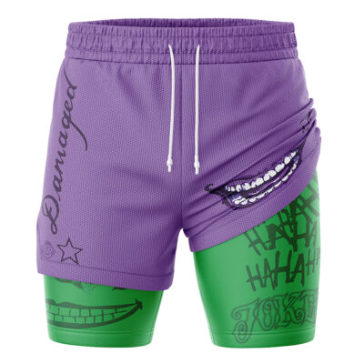 The Joker DC Comics 2-in-1 Performance Shorts feature purple and green colors, printed smiles, "Damaged" text on one leg, "Ha Ha Ha" graffiti on the other, and white drawstrings at the waistband.