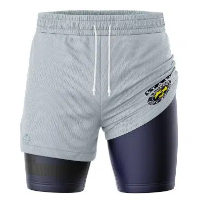The STARS Resident Evil 2-in-1 Performance Shorts feature light gray outer shorts with white drawstrings, worn over fitted dark navy compression shorts. A yellow, white, and black STARS emblem patch decorates the left side.