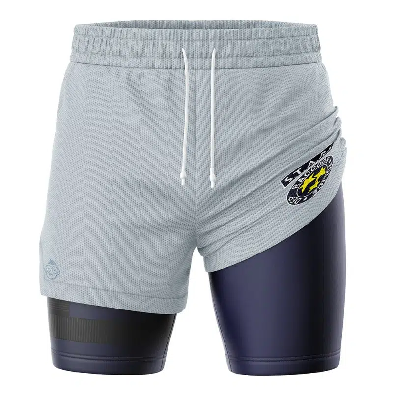 The STARS Resident Evil 2-in-1 Performance Shorts feature light gray outer shorts with white drawstrings, worn over fitted dark navy compression shorts. A yellow, white, and black STARS emblem patch decorates the left side.