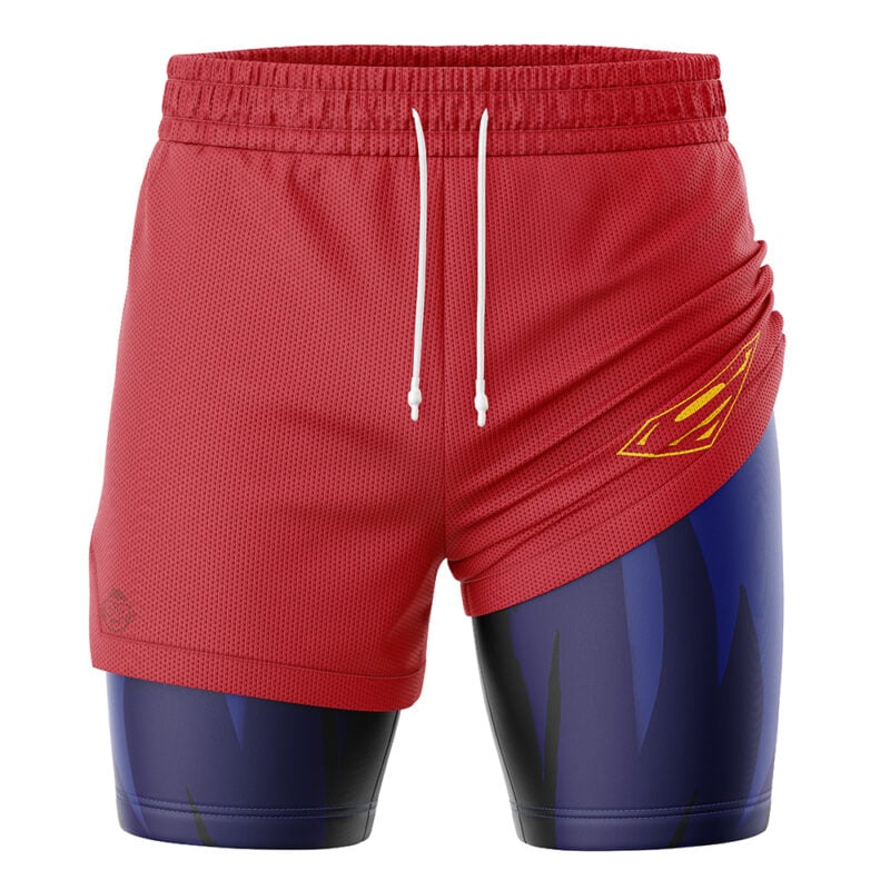 The Superman DC Comics 2-in-1 Performance Shorts feature red athletic shorts with white drawstrings over navy-blue compression shorts. The right leg displays a yellow stylized flame design, and the compression layer has a jagged dark pattern.