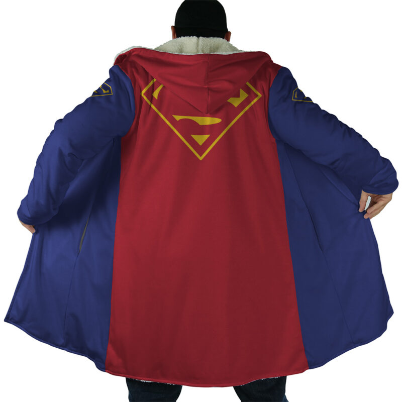 A person stands with their back to the camera, wearing the Superman DC Comics Dream Cloak Coat—featuring a long blue and red design, gold Superman logo on the back, blue inner lining, and a cape-like red back.