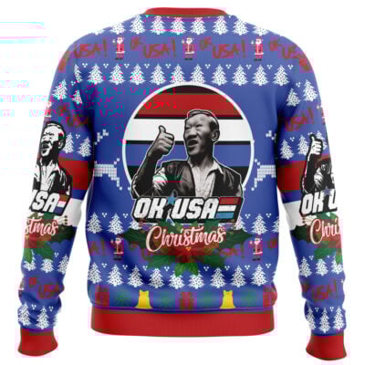 The Christmas Bloodsport Ugly Christmas Sweater features a black-and-white man giving a thumbs up with "OK USA Christmas" text, set on a red, white, and blue background with snowflakes, trees, and bells.