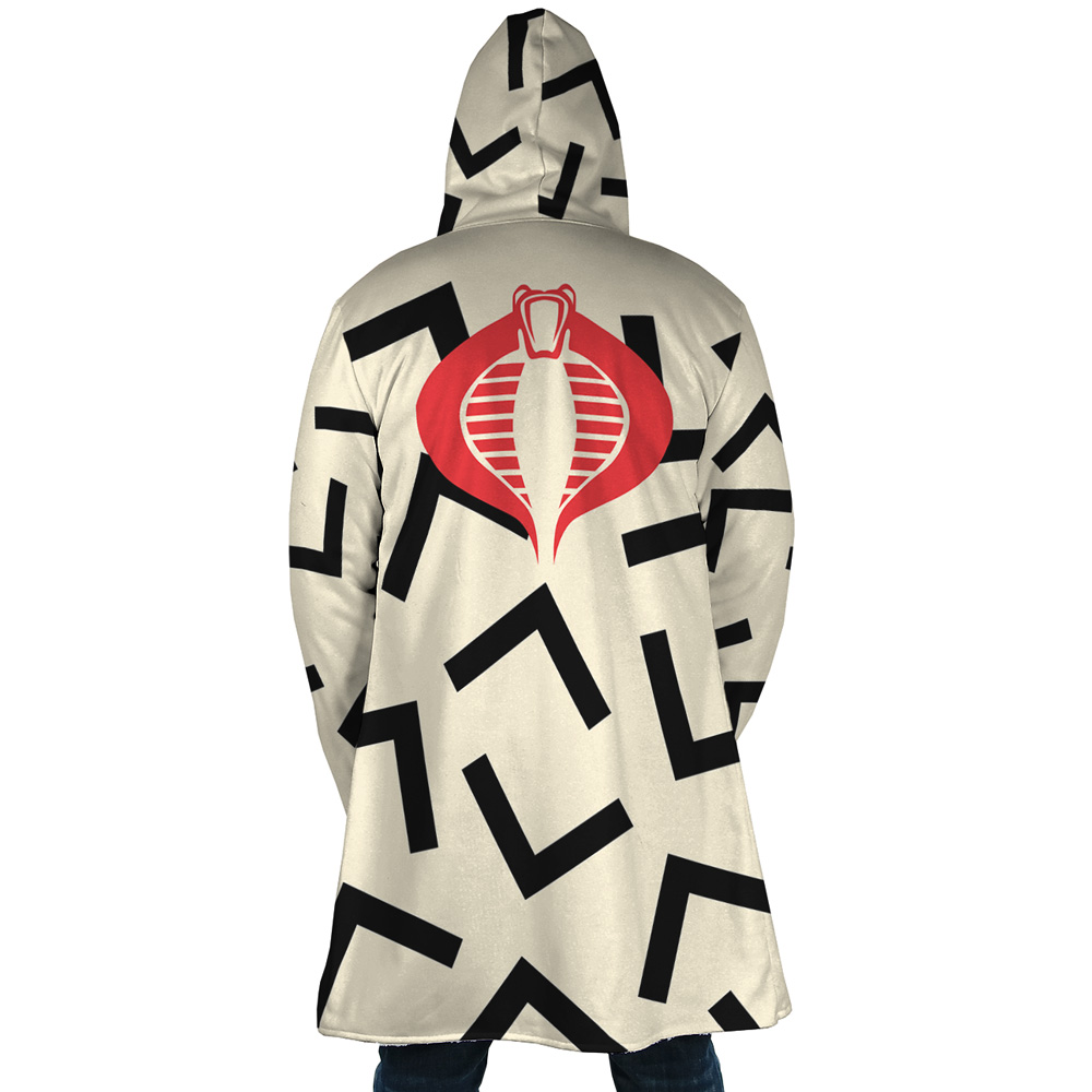 A person stands with their back to the camera wearing the Snow Cat Cosplay GI Joe Dream Cloak Coat, featuring a beige hood, bold black geometric patterns, and a large red cobra emblem on the back.
