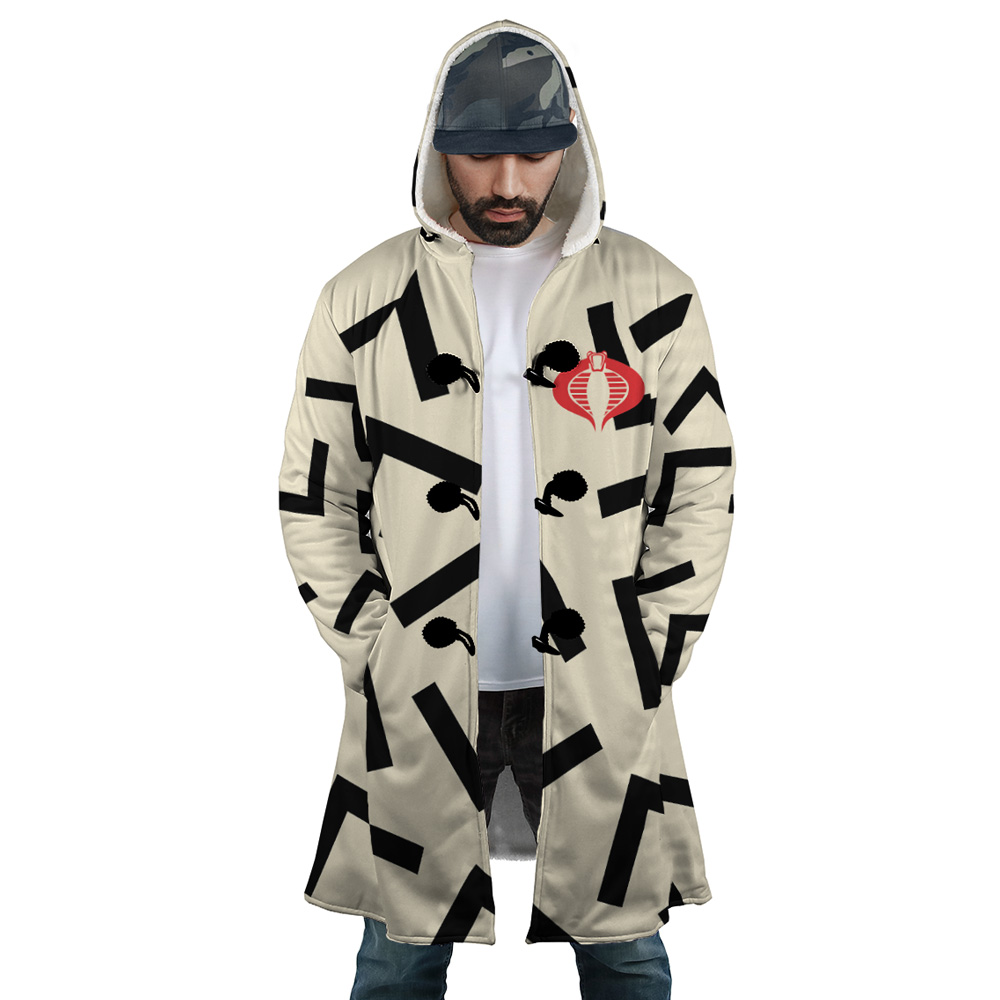 A man stands with hands in pockets, looking down, wearing the Snow Cat Cosplay GI Joe Dream Cloak Coat—a long, light-colored hooded coat with black abstract patterns and a red snake emblem—paired with a white shirt and camouflage cap.