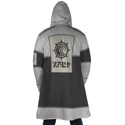 A person stands with their back to the camera, wearing the Sidon The Legend of Zelda Dream Cloak Coat—a long, hooded gray and black coat featuring bold geometric patterns and stylized symbols on the back and sleeve.