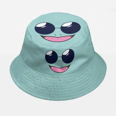 The Squirtle Squad Pokemon Custom Bucket Hat is a light blue hat featuring a cartoon frog-like face with big black eyes, round glasses, and a wide smiling mouth with a pink tongue.