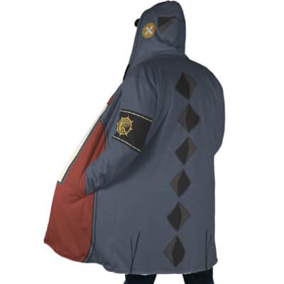 A person wears the Jabber Wonger Cosplay Gachiakuta Dream Cloak Coat, featuring a blue-gray hooded cloak with black diamond shapes on the back, a stitched patch on the hood, a black armband with yellow symbol, and a brown-red section on one side.