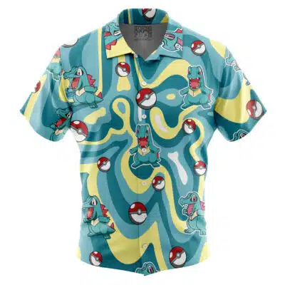 A vibrant short-sleeve button-up Hawaiian shirt featuring Totodile Pokémon and Poké Balls on a blue, yellow, and teal wavy background. Product name: Default Button Up Hawaiian Shirt (Copy).