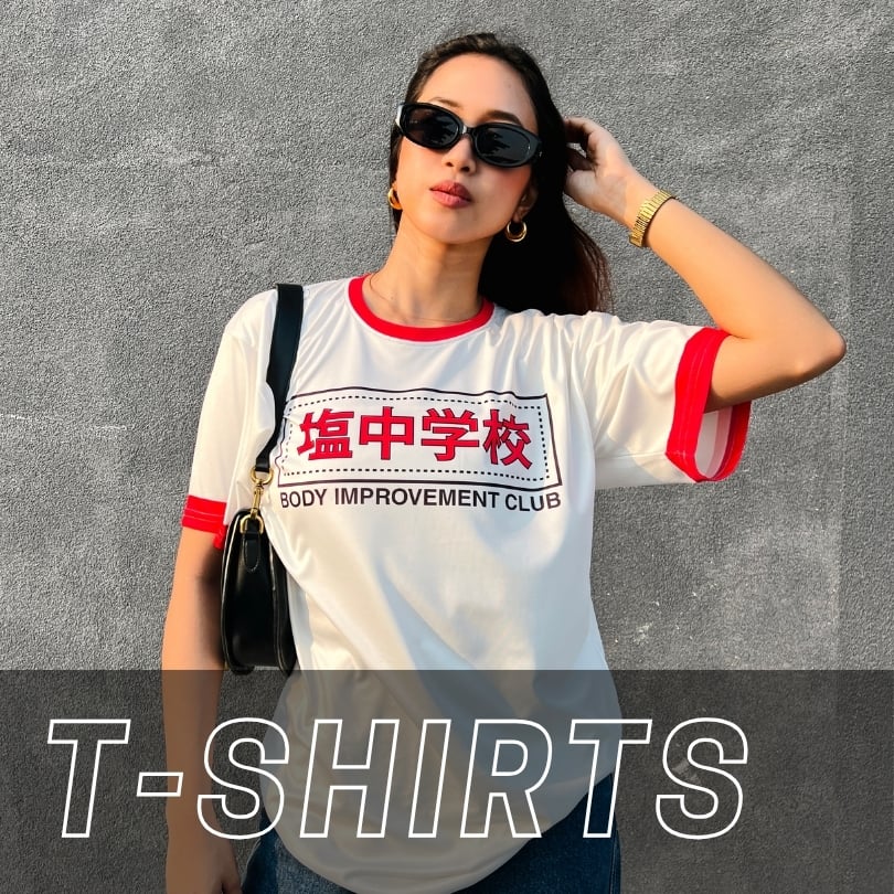 A person wearing a white ringer t-shirt with red trim and a graphic that reads Body Improvement Club in Japanese and English text.