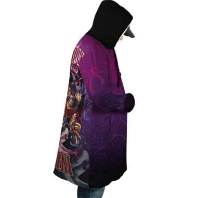A person wearing a Heishiro Mitsurugi Soulcalibur Dream Cloak Coat featuring a large, vibrant graphic of a character with a sword on the back and purple patterned designs on the sides.